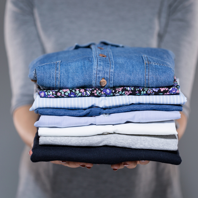 a person holding a stack of clothing