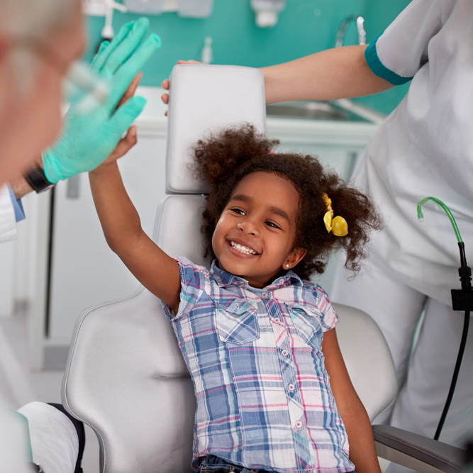 a young girl high-fives a dentist